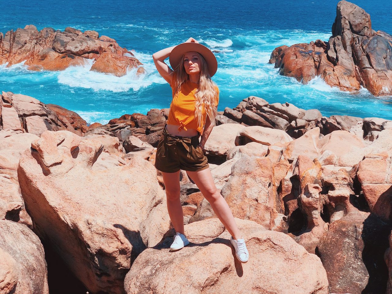 beautiful blonde traveler girl wearing hat and yellow t shirt at the rocky beach in australia.jpg